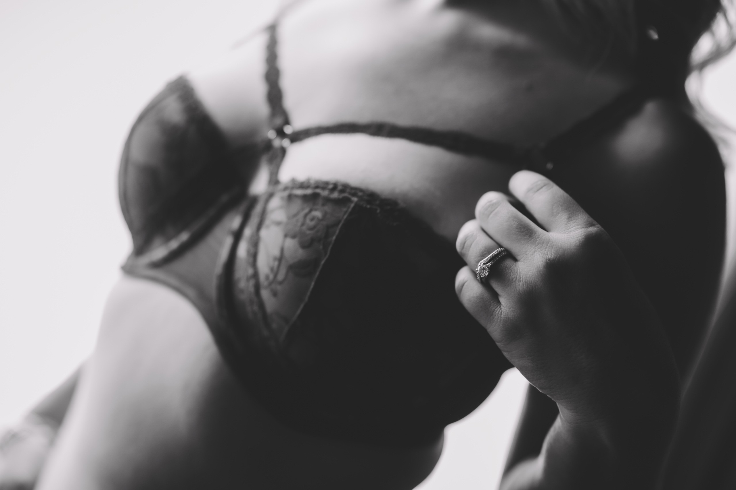 black and white close up of a woman's chest with her left hand and weddings bands in focus